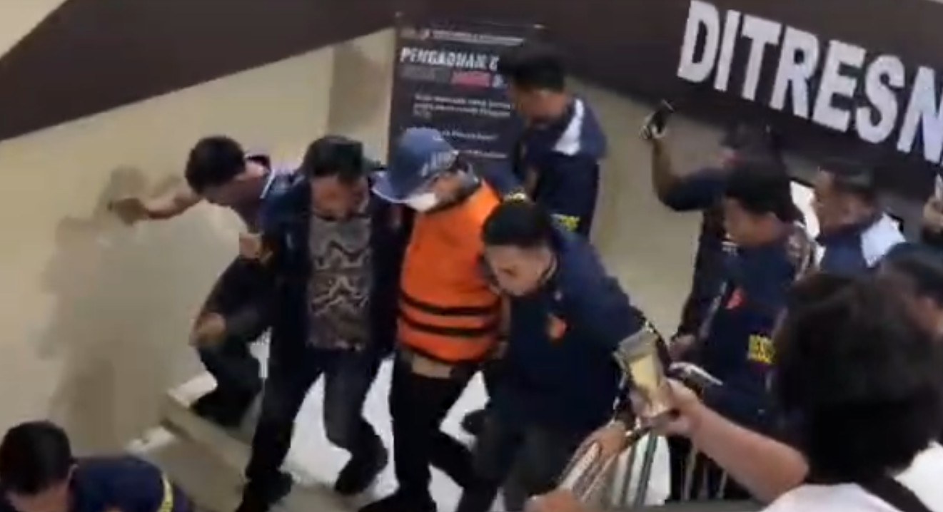 Dugaan Korupsi 387 Honorer Metro, Welly Adiwantra Digiring ke Tahanan Polda **LAMPUNG —** Rompi tahanan berwarna kuning melekat di tubuh Welly Adiwantra. Mengenakan masker dan topi, Sekretaris Daerah (Sekda) Lampung Tengah itu digiring menuju ruang tahanan Polda Lampung, Jumat (18/9/2026). Langkah Welly menuju tahanan menjadi penanda babak baru kasus dugaan korupsi rekrutmen tenaga honorer di lingkungan Pemerintah Kota (Pemkot) Metro. Sebelumnya, Welly menjalani pemeriksaan penyidik Subdit III Tipikor Ditreskrimsus Polda Lampung sejak pukul 08.00 WIB hingga 17.19 WIB. Setelah pemeriksaan rampung, statusnya berujung pada penahanan. Direktur Reserse Kriminal Khusus (Dirreskrimsus) Polda Lampung, Kombes Pol Heri Rusyaman, membenarkan pemeriksaan terhadap Welly. “Iya, benar hari ini menjalani pemeriksaan,” ujar Heri. Perkara tersebut berkaitan dengan dugaan korupsi rekrutmen tenaga honorer ketika Welly menjabat sebagai Kepala Badan Kepegawaian dan Pengembangan Sumber Daya Manusia (BKPSDM) Kota Metro. Kasubdit III Tipikor Ditreskrimsus Polda Lampung, AKBP Donny Hendridunand, mengatakan penyidik menduga terjadi rekrutmen tenaga honorer atau tenaga kontrak pada tahun anggaran 2024–2025 yang tidak sesuai dengan ketentuan perundang-undangan. “Total ada 387 honorer, tenaga kontrak. Sejak tahun 2023 itu dilarang, karena ada penataan,” kata Donny. Rekrutmen tersebut berkaitan dengan kebijakan penataan tenaga non-ASN sebagaimana diatur dalam Undang-Undang Nomor 20 Tahun 2023 tentang Aparatur Sipil Negara (ASN). Dugaan penyimpangan itu kemudian berujung pada kerugian keuangan negara. Berdasarkan hasil audit Badan Pengawasan Keuangan dan Pembangunan (BPKP) Perwakilan Lampung, kerugian negara dalam perkara tersebut mencapai **Rp7,38 miliar**. Angka itu menjadi salah satu titik penting dalam perkara yang kini menjerat Welly. Sebab, rekrutmen ratusan tenaga kontrak tersebut diduga berdampak pada penggunaan anggaran daerah. ### Dijerat Pasal Korupsi Polda Lampung masih memproses berkas perkara Welly. Penyidik juga telah menindaklanjuti hasil penelitian dari jaksa penuntut umum (JPU). Welly dijerat Pasal 2 ayat (1) atau Pasal 3 juncto Pasal 18 Undang-Undang Nomor 31 Tahun 1999 tentang Pemberantasan Tindak Pidana Korupsi. Penyidik juga menerapkan Pasal 603 atau subsider Pasal 604 Undang-Undang Nomor 1 Tahun 2023 tentang Kitab Undang-Undang Hukum Pidana (KUHP). Penahanan Welly menjadi perkembangan terbaru dalam perkara dugaan korupsi rekrutmen 387 tenaga honorer di lingkungan Pemkot Metro. Dari ruang pemeriksaan, Welly kini berada di balik pintu tahanan Polda Lampung, sementara proses hukum terhadap perkara yang disebut menimbulkan kerugian negara Rp7,38 miliar itu masih berjalan. *(ela)*
